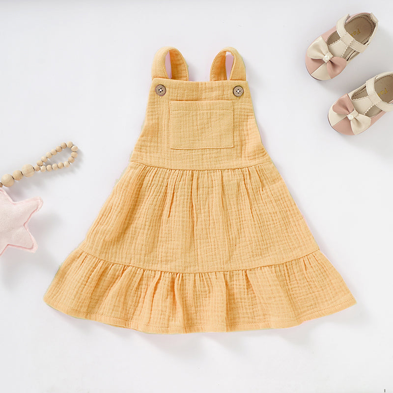 A soft and stylish Organic Cotton Muslin Baby Dress in three colors, featuring button straps and textured fabric, perfect for babies.