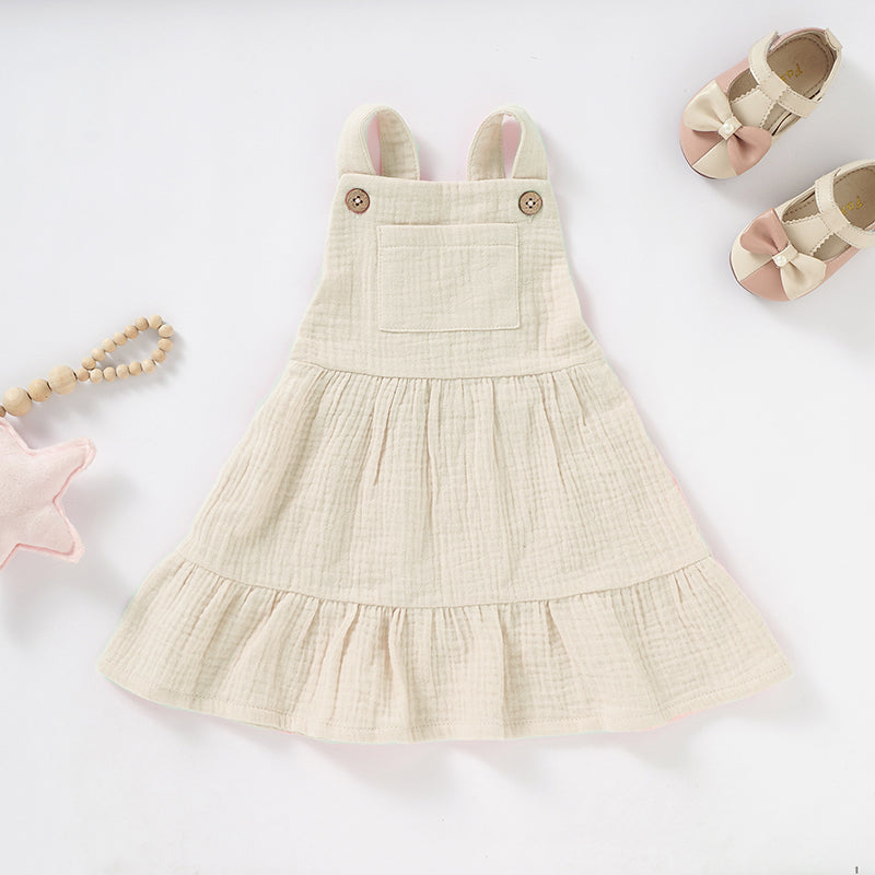 A soft and stylish Organic Cotton Muslin Baby Dress in three colors, featuring button straps and textured fabric, perfect for babies.