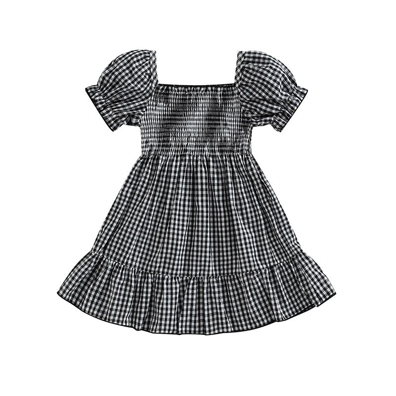 A stylish black plaid smocked dress featuring puff sleeves and a ruffle hem, perfect for girls' special occasions and everyday wear.