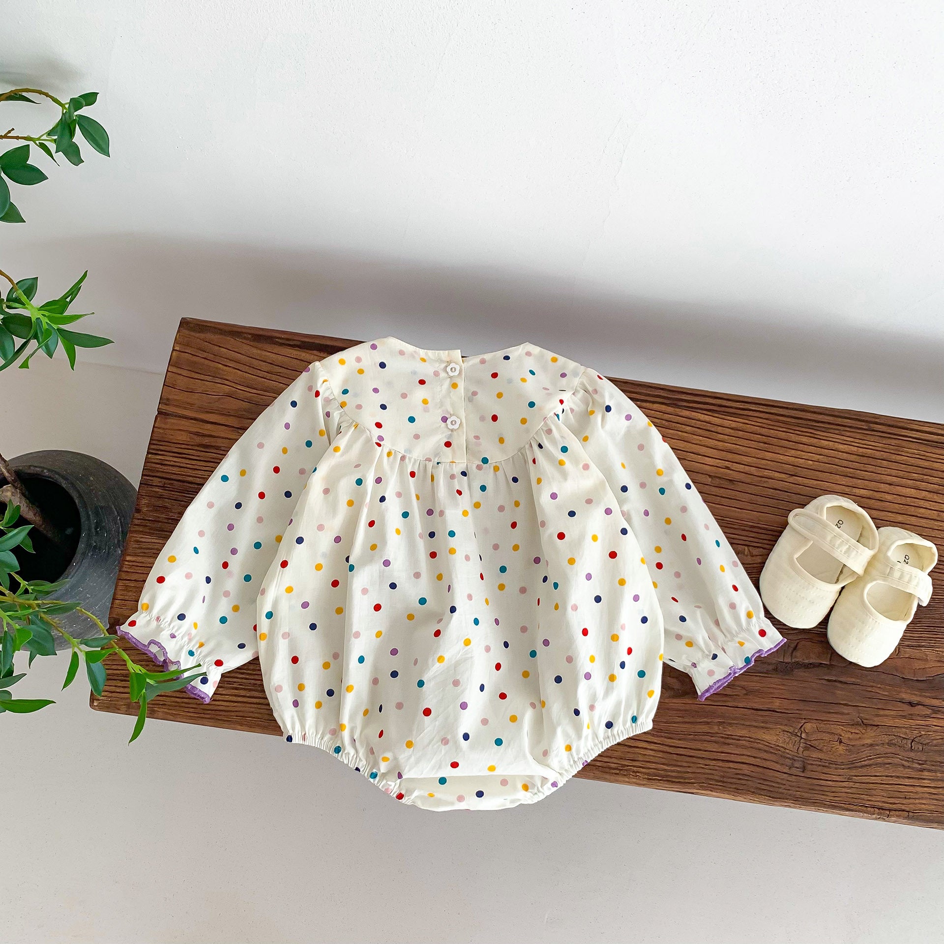 A cute baby girl wearing a long sleeve princess onesie with floral and solid patterns in white and pink colors.