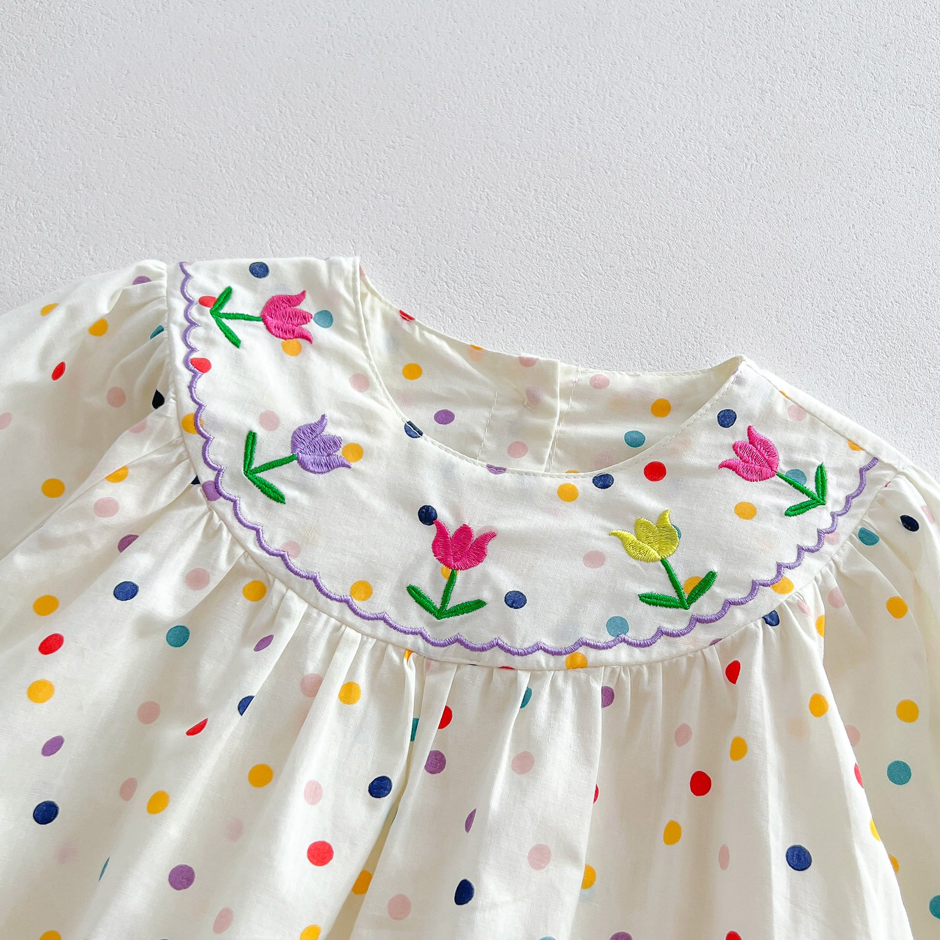 A cute baby girl wearing a long sleeve princess onesie with floral and solid patterns in white and pink colors.