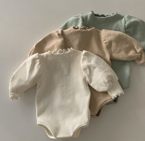 A soft ribbed baby bodysuit in green, ecru, and beige colors, showcasing its gentle fabric and stylish design.