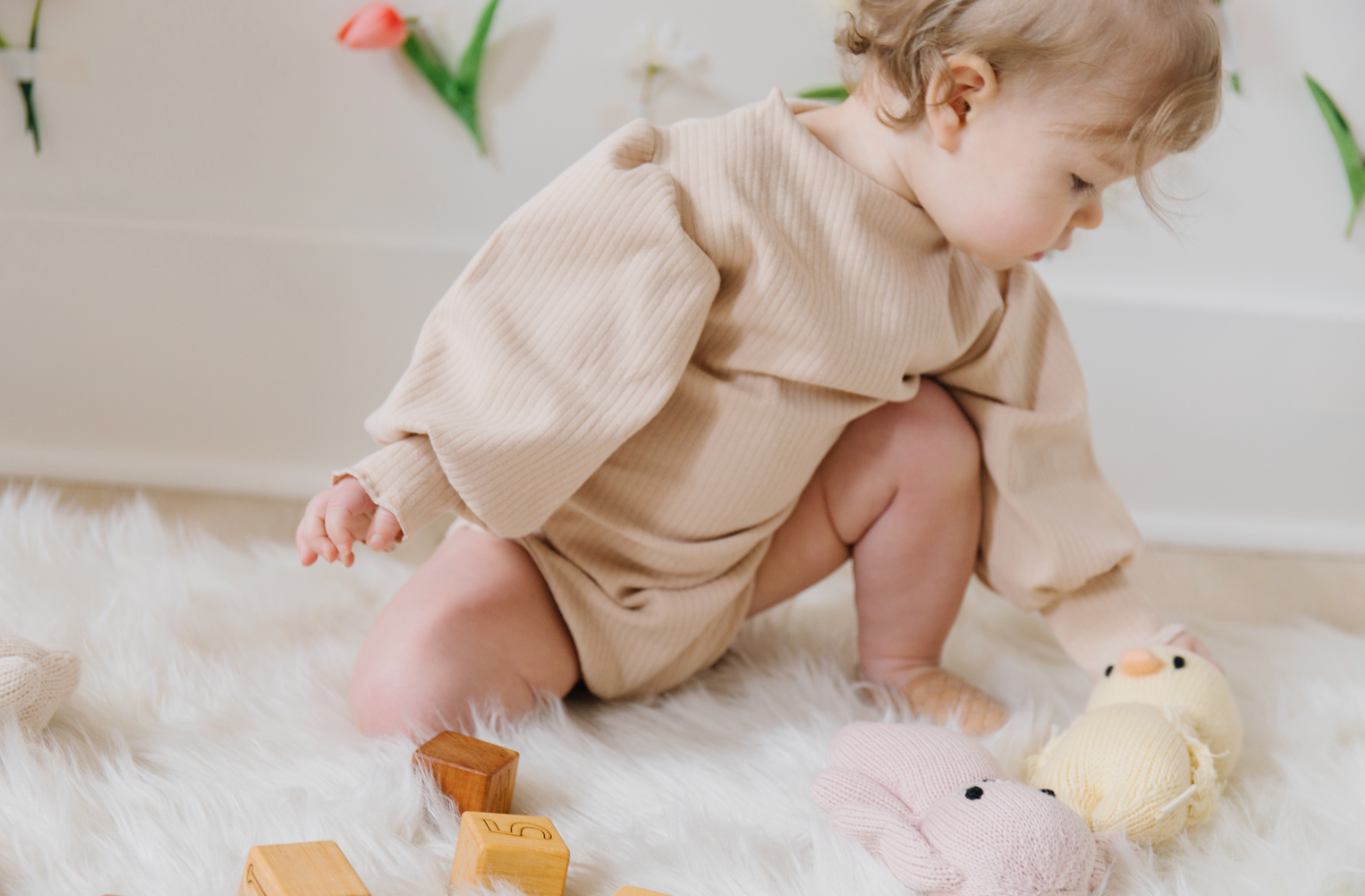 A soft ribbed baby bodysuit in green, ecru, and beige colors, showcasing its gentle fabric and stylish design.