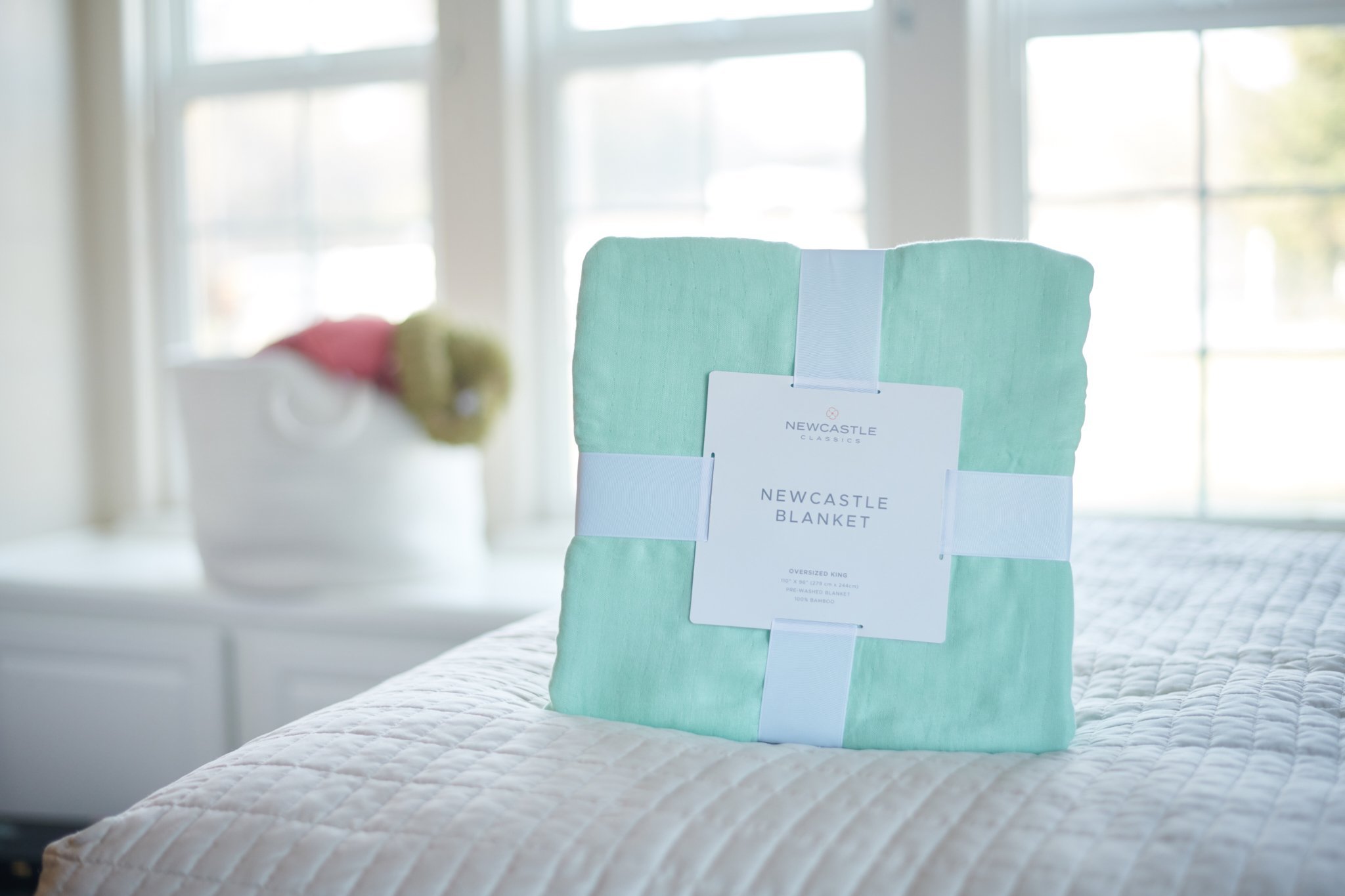 Seafoam green oversized queen bamboo bed blanket draped elegantly on a bed, showcasing its soft texture and beautiful color.