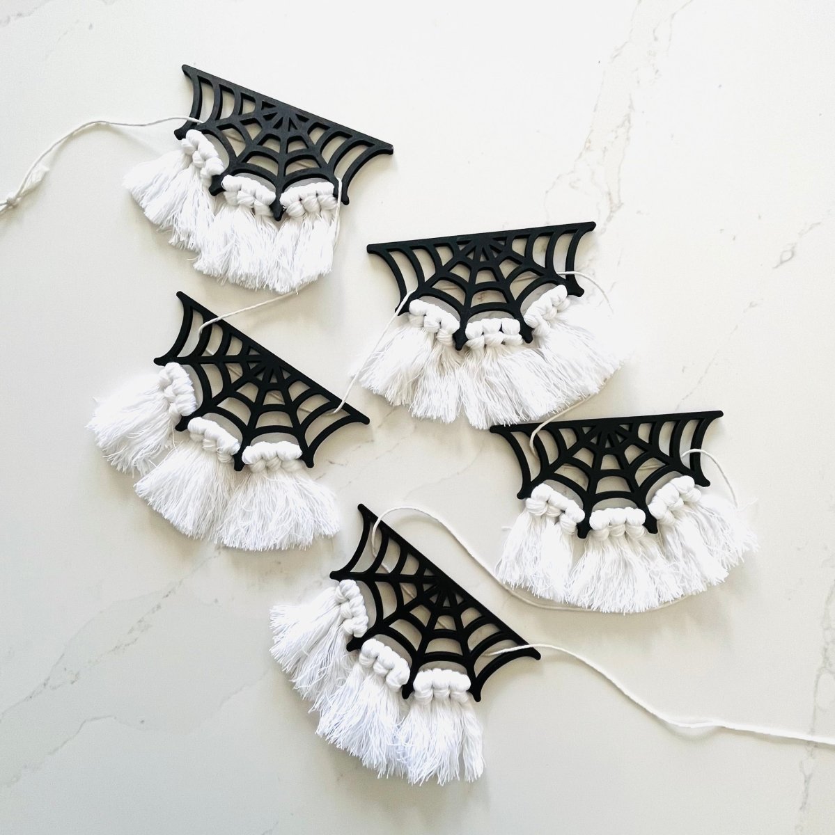 A beautifully crafted Spiderweb Macrame Garland featuring intricate laser-cut spiderweb designs strung on a strong cotton cord, perfect for Halloween decor.