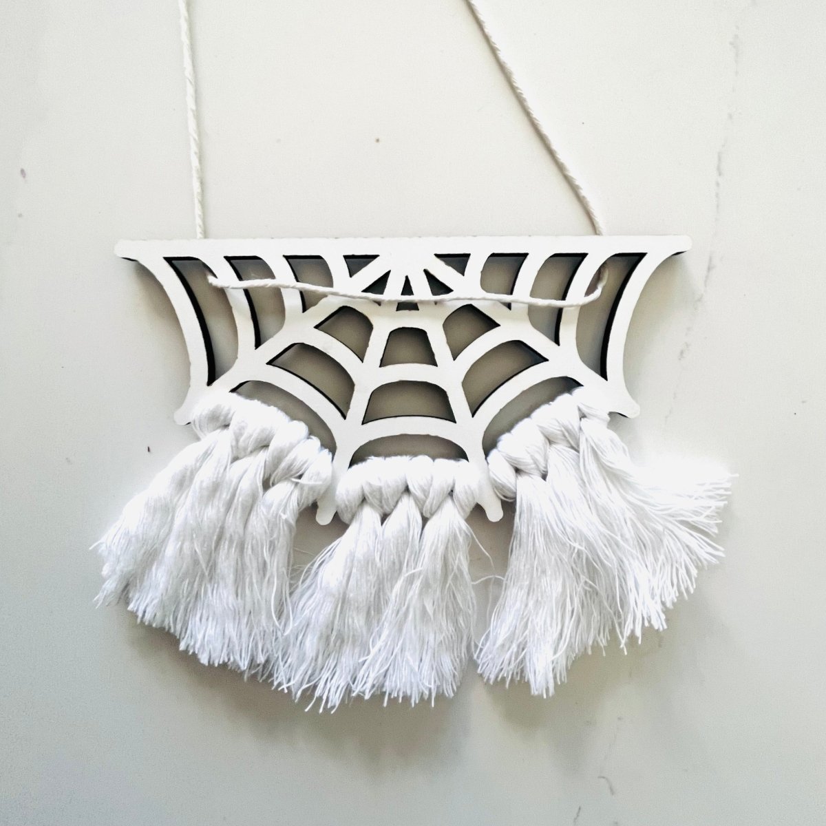A beautifully crafted Spiderweb Macrame Garland featuring intricate laser-cut spiderweb designs strung on a strong cotton cord, perfect for Halloween decor.