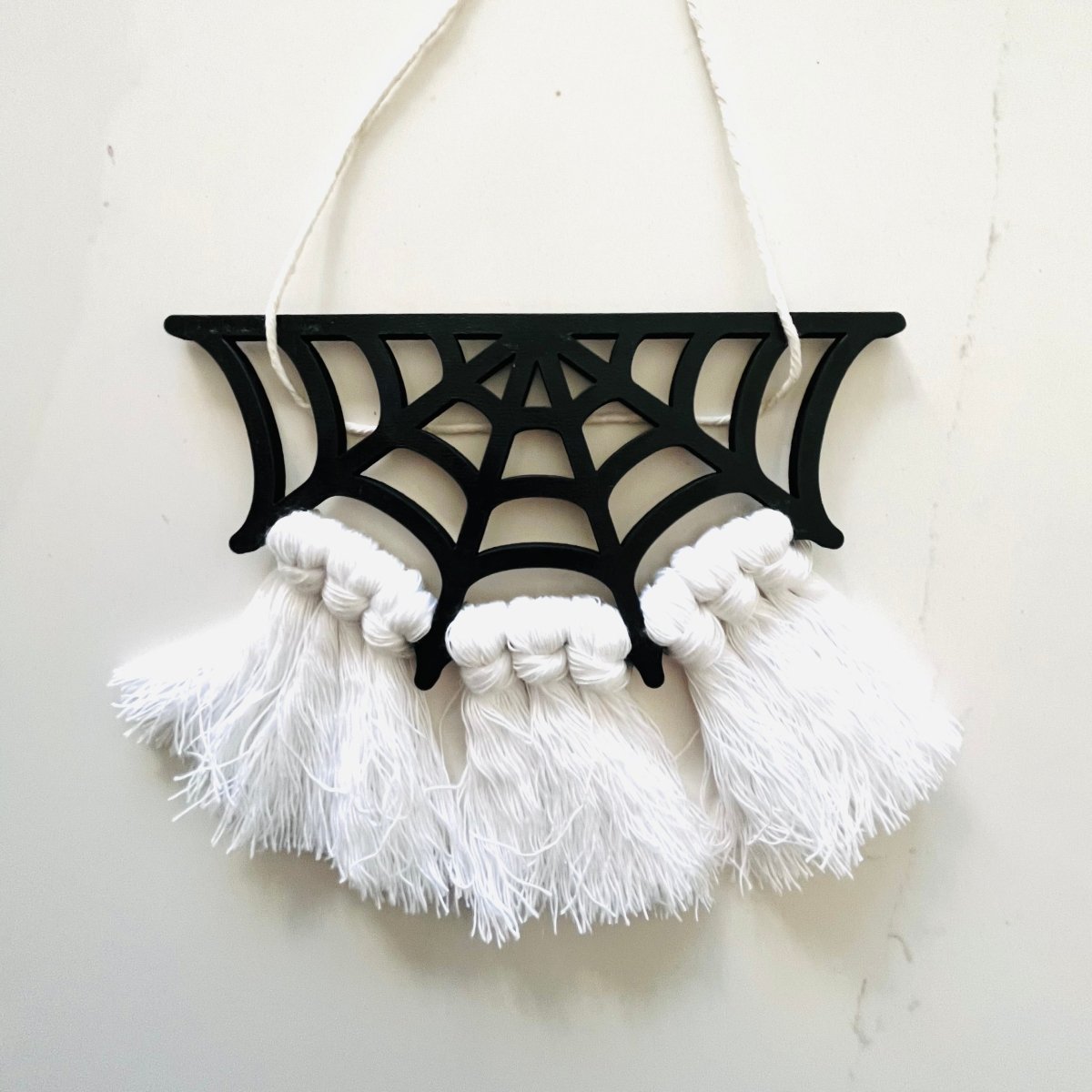 A beautifully crafted Spiderweb Macrame Garland featuring intricate laser-cut spiderweb designs strung on a strong cotton cord, perfect for Halloween decor.