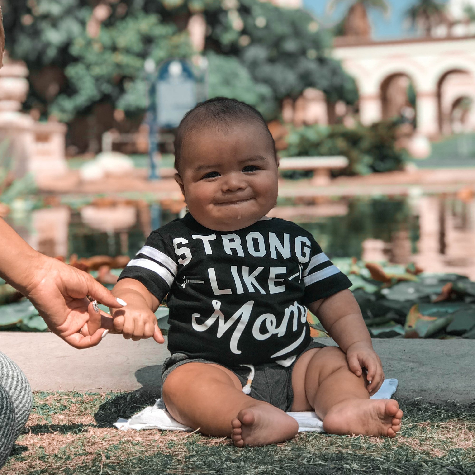 A stylish 'STRONG LIKE MOM' baby boy jumpsuit in black and white, showcasing its soft cotton blend fabric and trendy design.