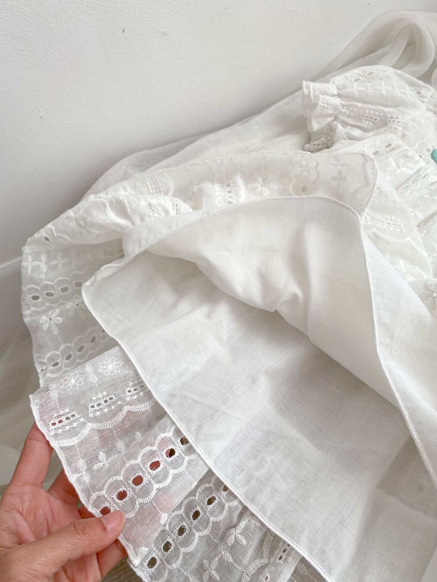 A cute summer dress for baby girls featuring floral embroidery and hollow-out short sleeves, made from soft cotton in white color.