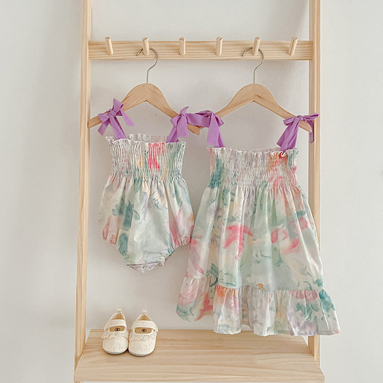 A beautiful summer dress for baby girls featuring a sleeveless off-shoulder design with a vibrant floral pattern in purple and beige colors.