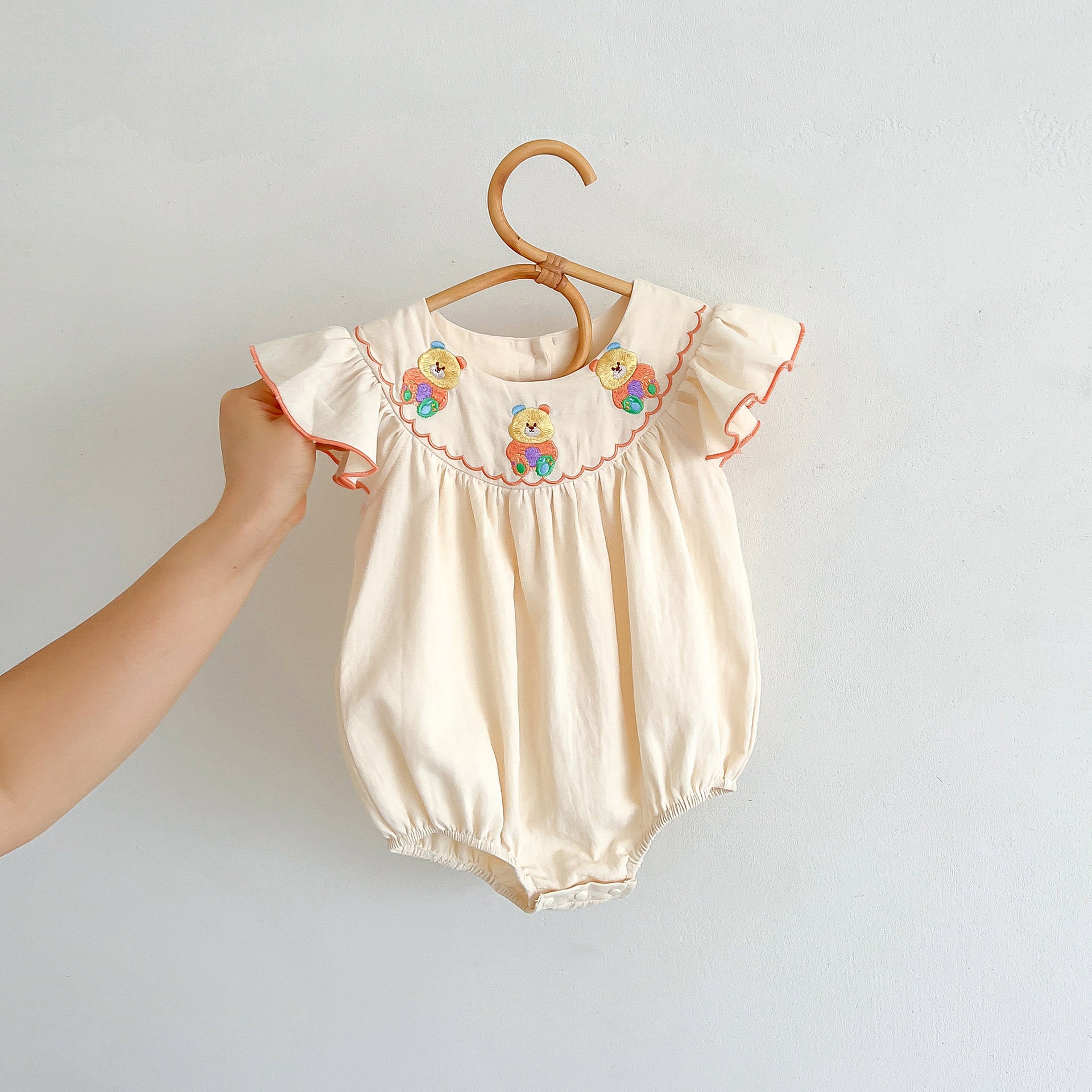 A cute apricot teddy for baby girls featuring fly sleeves and a cartoon pattern, perfect for summer wear.