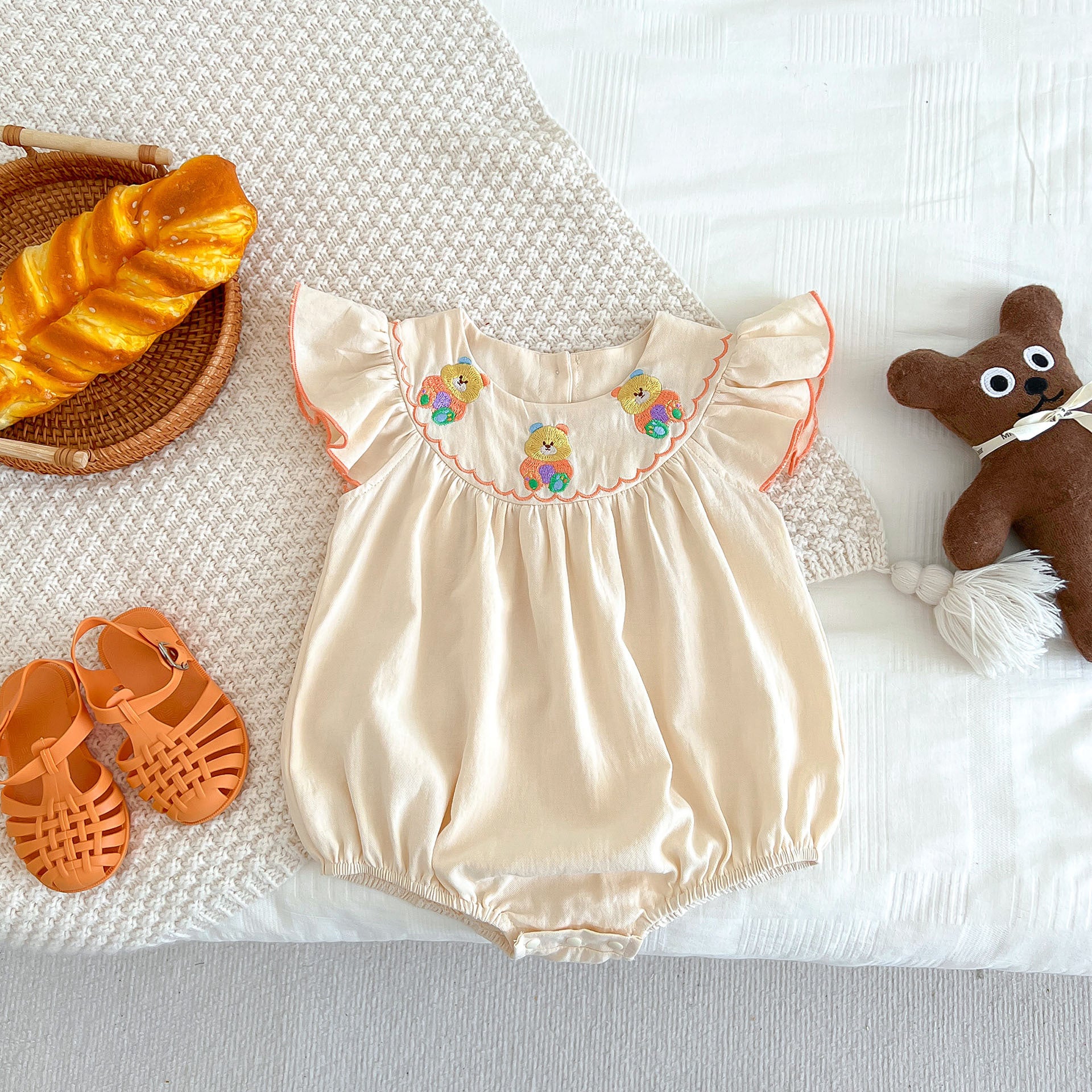 A cute apricot teddy for baby girls featuring fly sleeves and a cartoon pattern, perfect for summer wear.