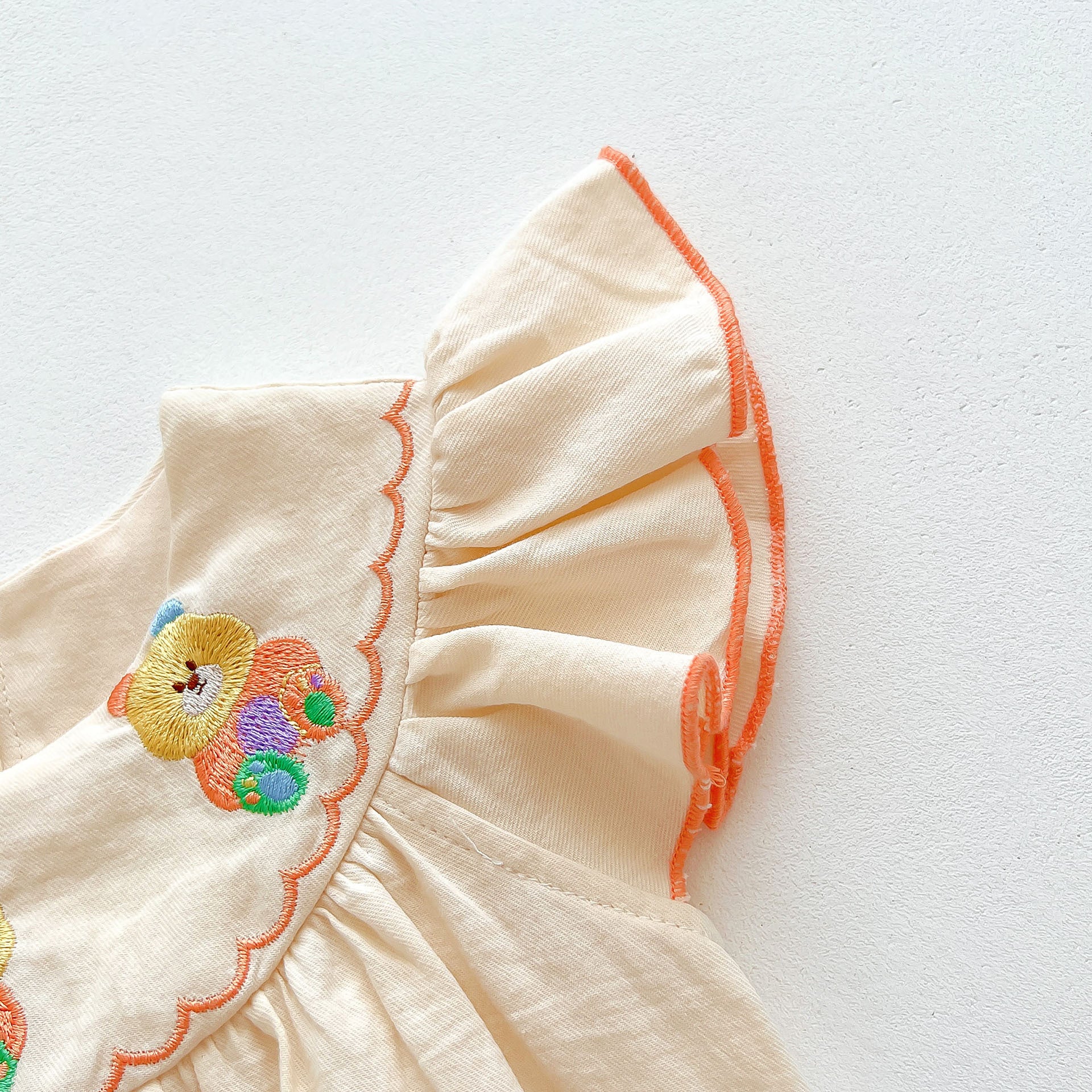 A cute apricot teddy for baby girls featuring fly sleeves and a cartoon pattern, perfect for summer wear.
