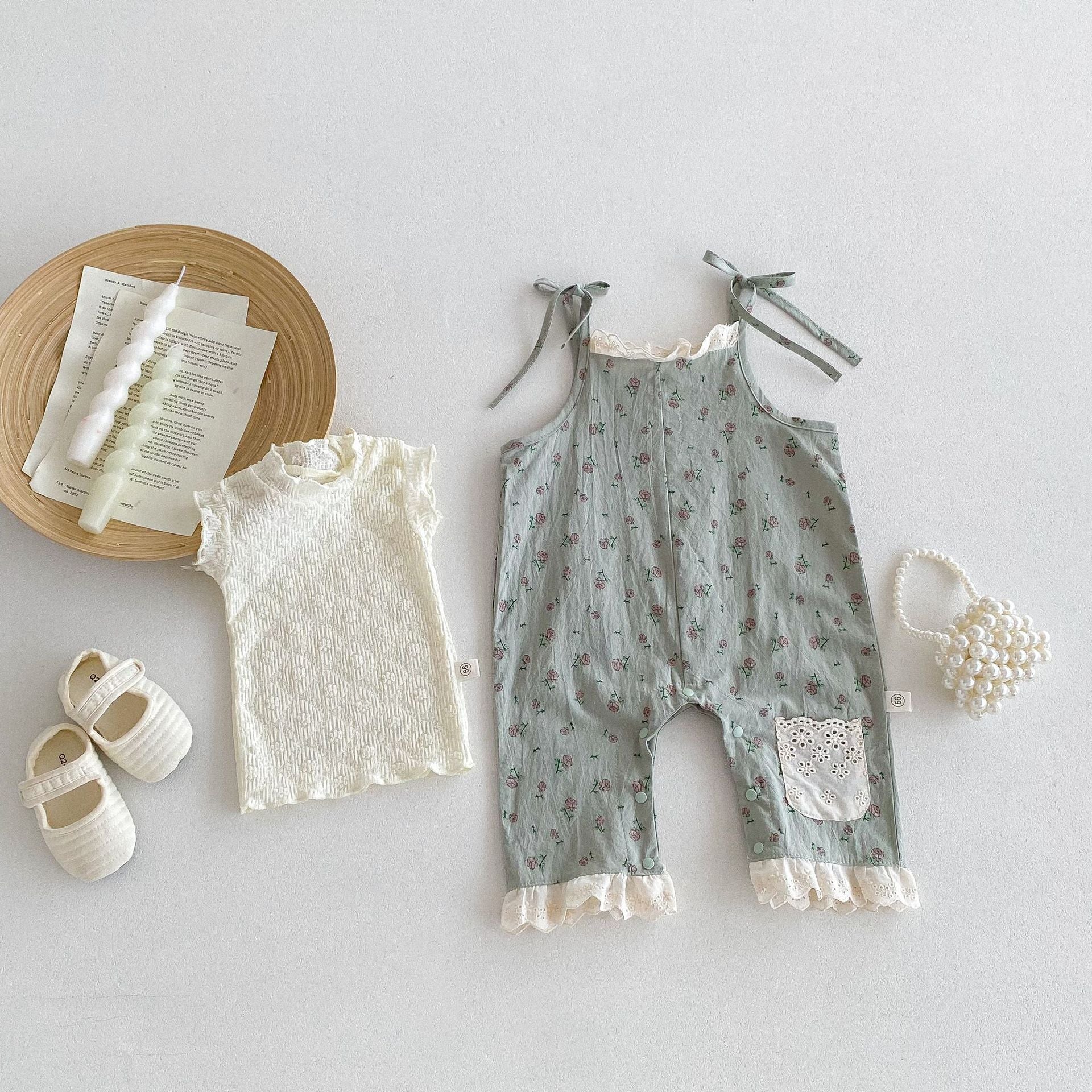 A cute baby girl wearing a green sleeveless floral pattern strap romper, perfect for summer outings.