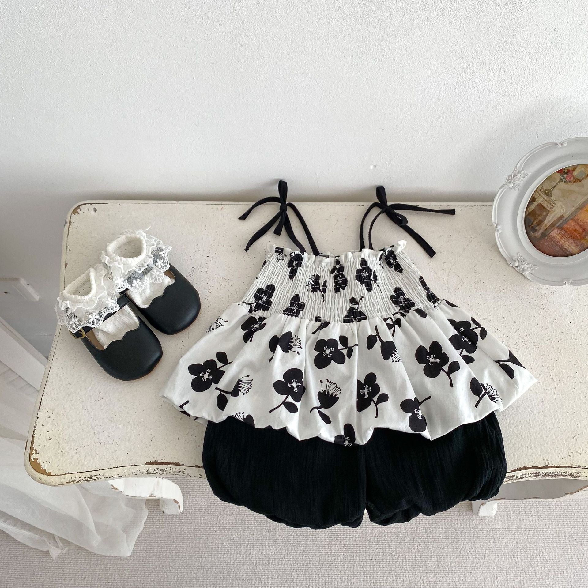A stylish black sleeveless floral print strap top for baby girls, perfect for summer wear.