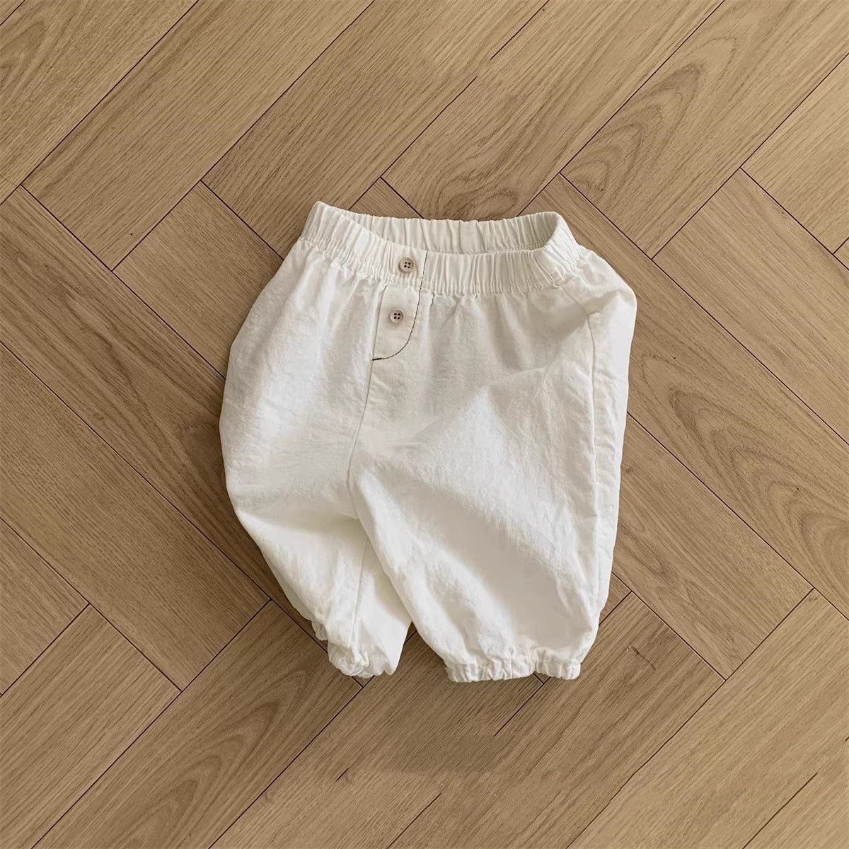 A collection of soft cotton baby clothing in solid colors including white, pink, grey, and brown, suitable for both boys and girls.