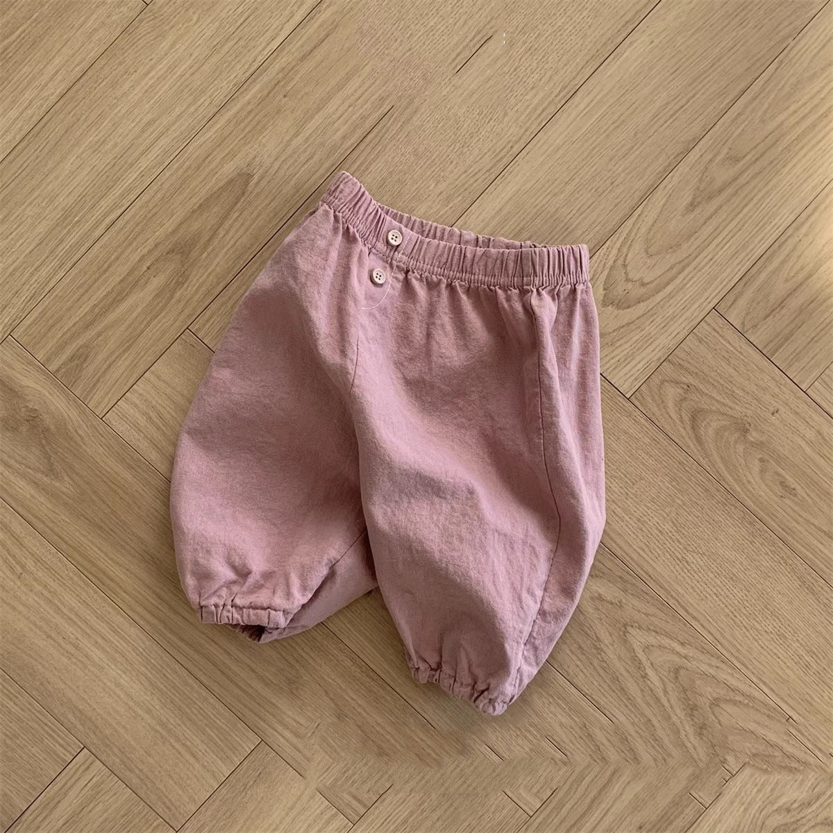 A collection of soft cotton baby clothing in solid colors including white, pink, grey, and brown, suitable for both boys and girls.