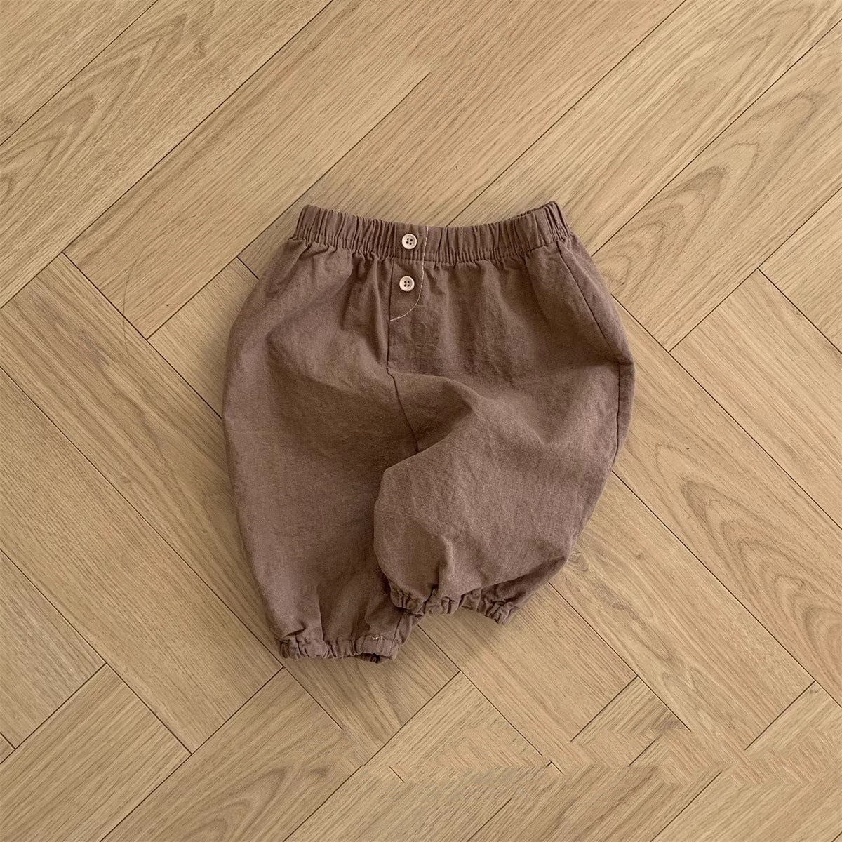 A collection of soft cotton baby clothing in solid colors including white, pink, grey, and brown, suitable for both boys and girls.