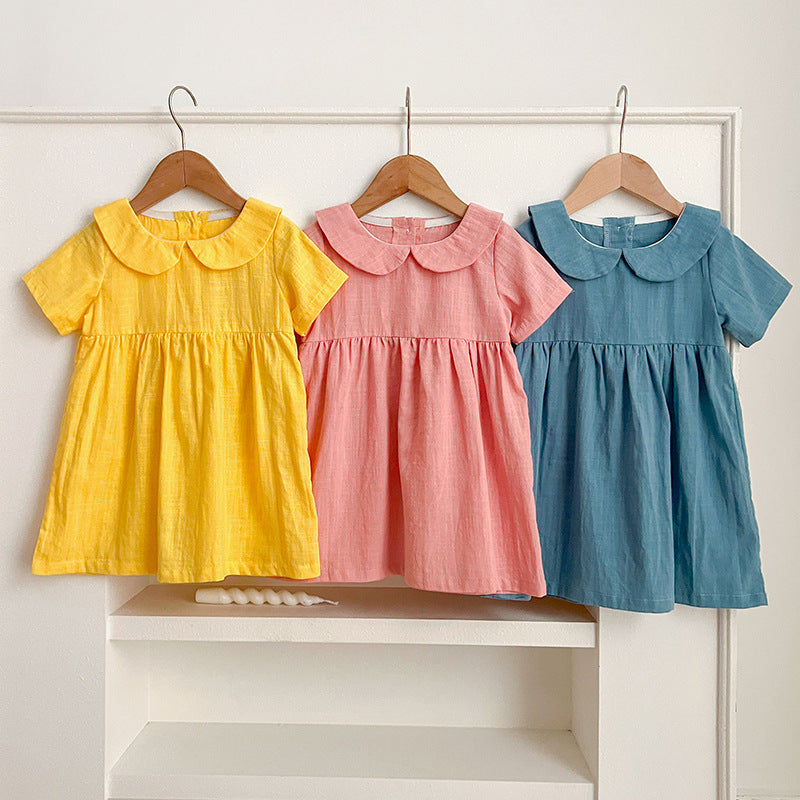 A vibrant collection of girls' solid color short sleeves tops featuring a Peter Pan collar in pink, blue, and yellow.