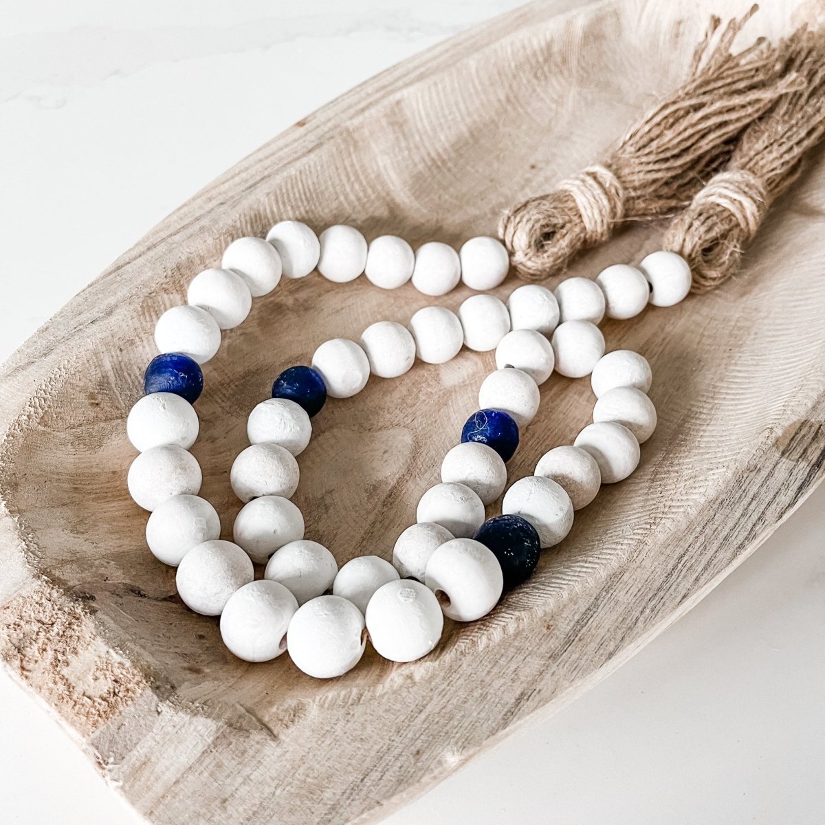 A beautifully handcrafted Whitewashed Wood Bead Garland featuring Jumbo Cobalt Blue Recycled Glass beads, perfect for coastal decor.