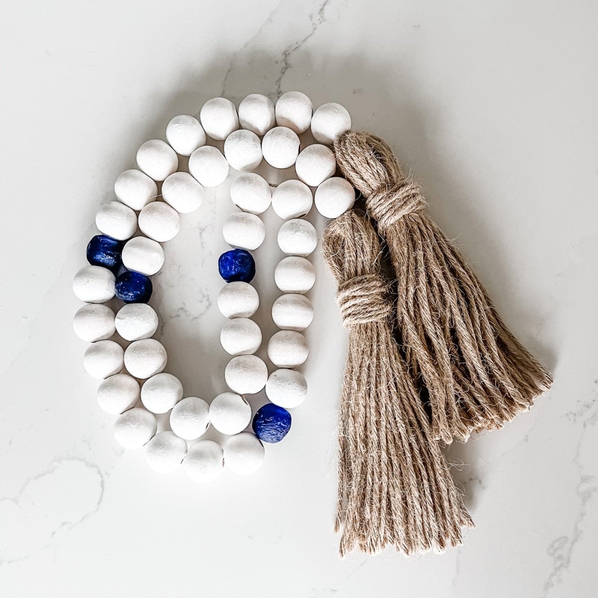 A beautifully handcrafted Whitewashed Wood Bead Garland featuring Jumbo Cobalt Blue Recycled Glass beads, perfect for coastal decor.