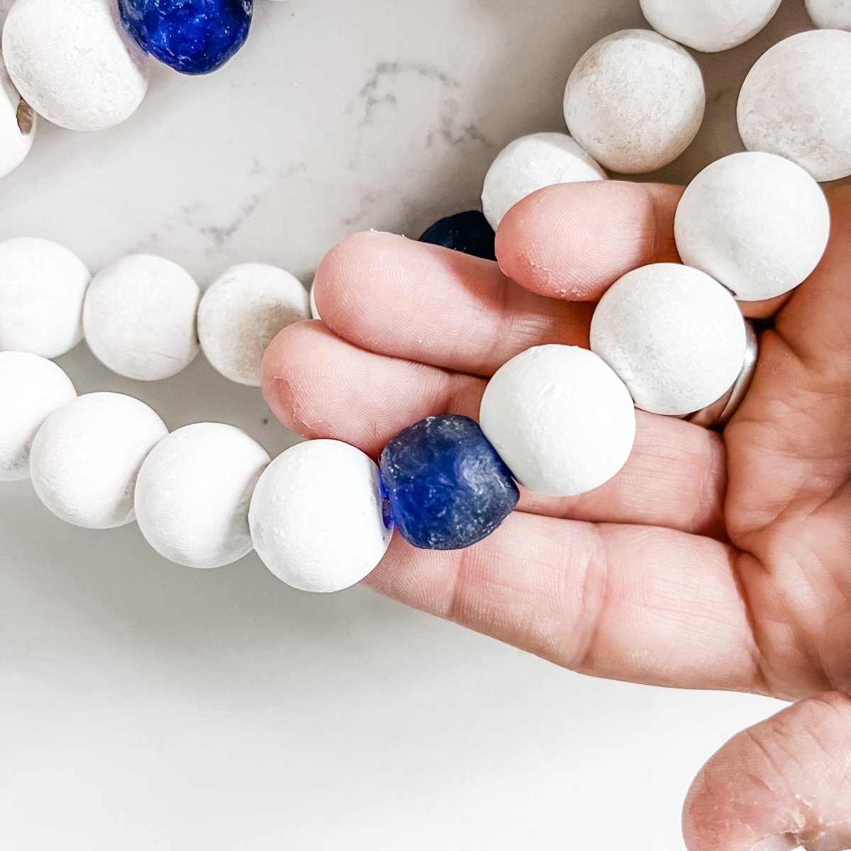 A beautifully handcrafted Whitewashed Wood Bead Garland featuring Jumbo Cobalt Blue Recycled Glass beads, perfect for coastal decor.