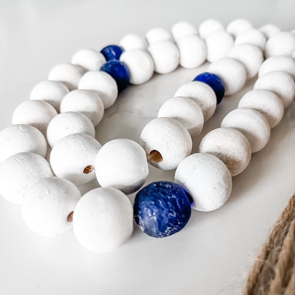 A beautifully handcrafted Whitewashed Wood Bead Garland featuring Jumbo Cobalt Blue Recycled Glass beads, perfect for coastal decor.
