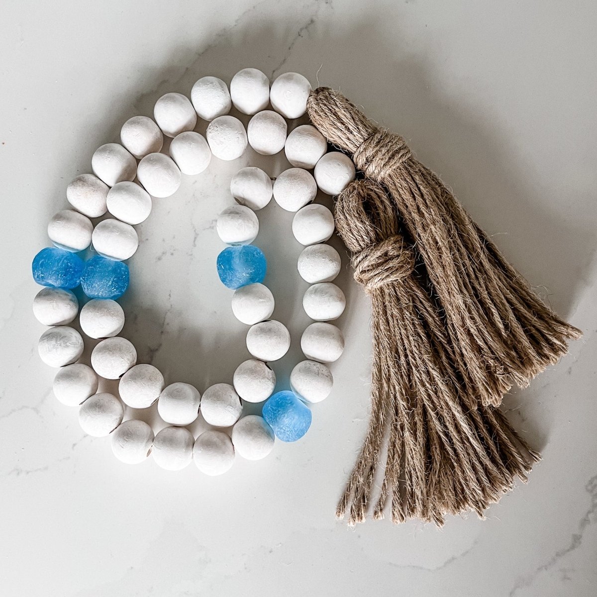 A beautiful Whitewashed Wood Bead Garland featuring Jumbo Ice Blue Recycled Glass Beads, perfect for coastal decor.