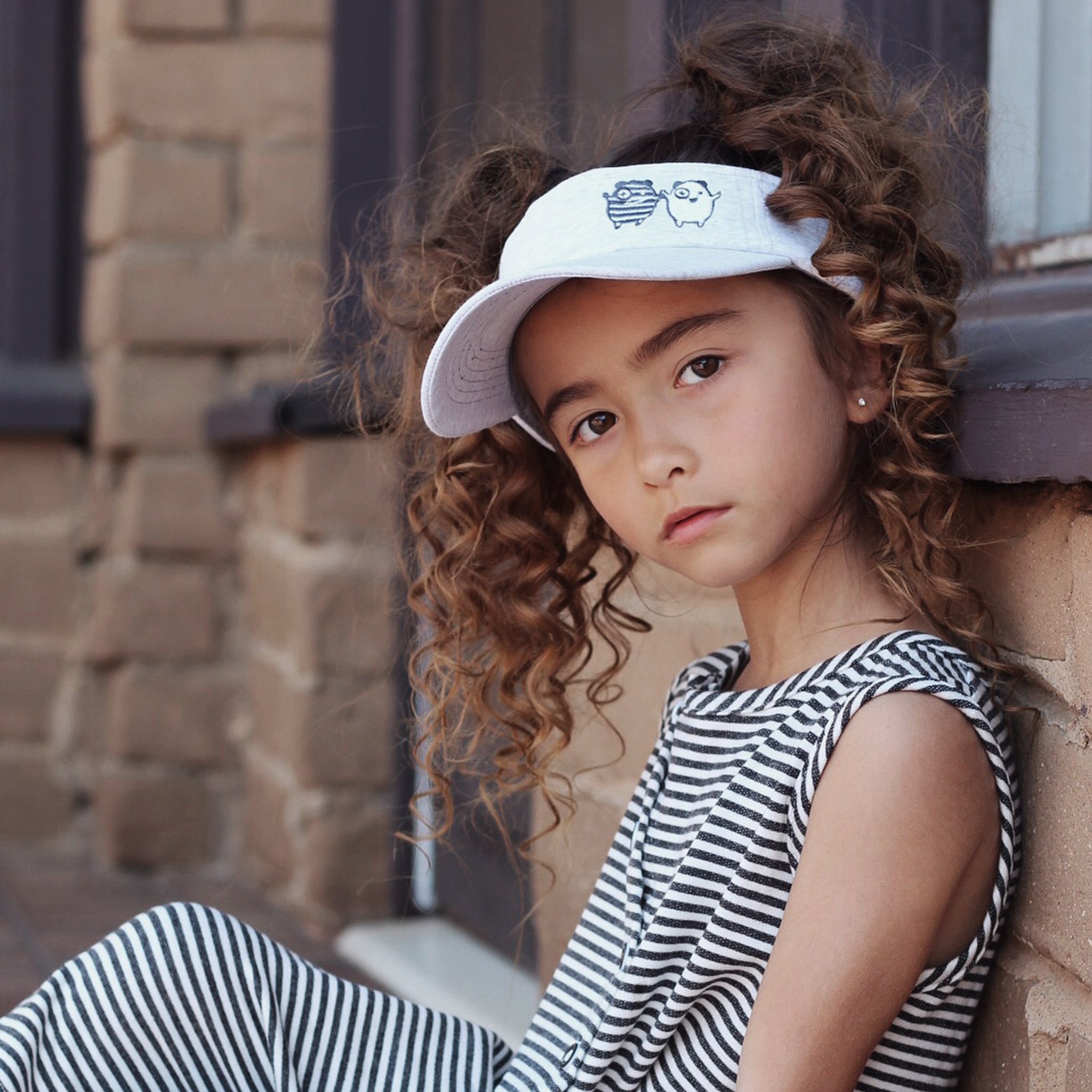 X + O Sun Visor featuring embroidered monsters and adjustable strap, perfect for sunny days.
