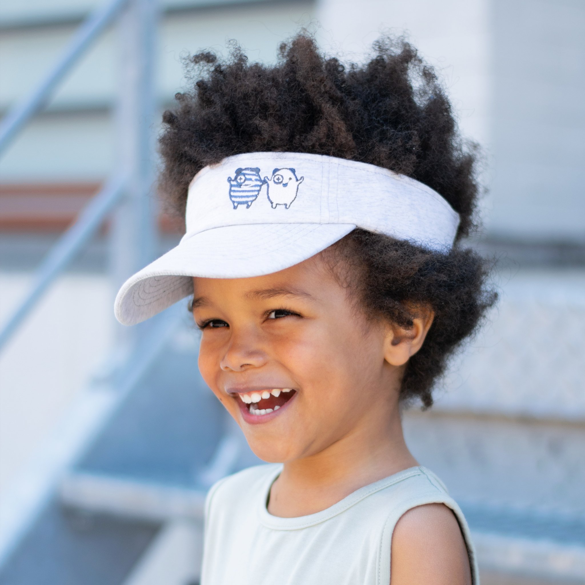 X + O Sun Visor featuring embroidered monsters and adjustable strap, perfect for sunny days.