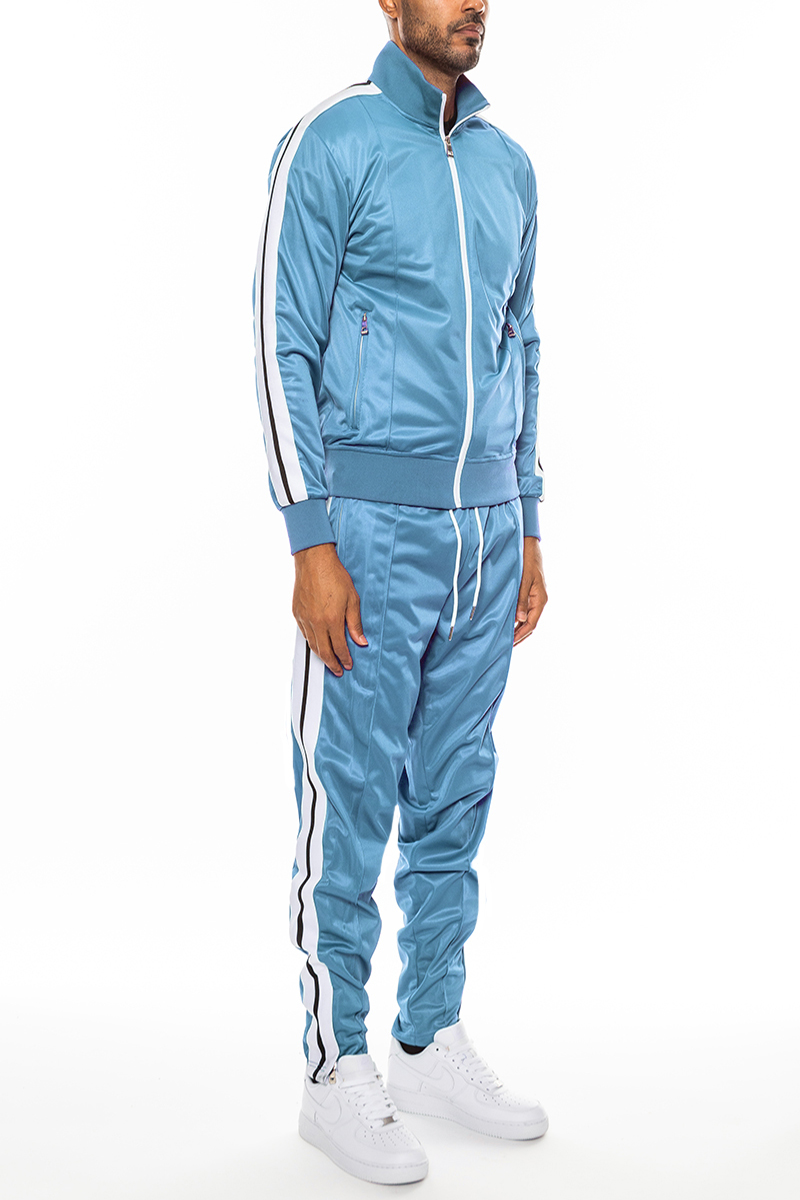 A stylish striped tape front pleat track suit featuring a full zip jacket, elastic waist, and ankle zippers, displayed on a mannequin.