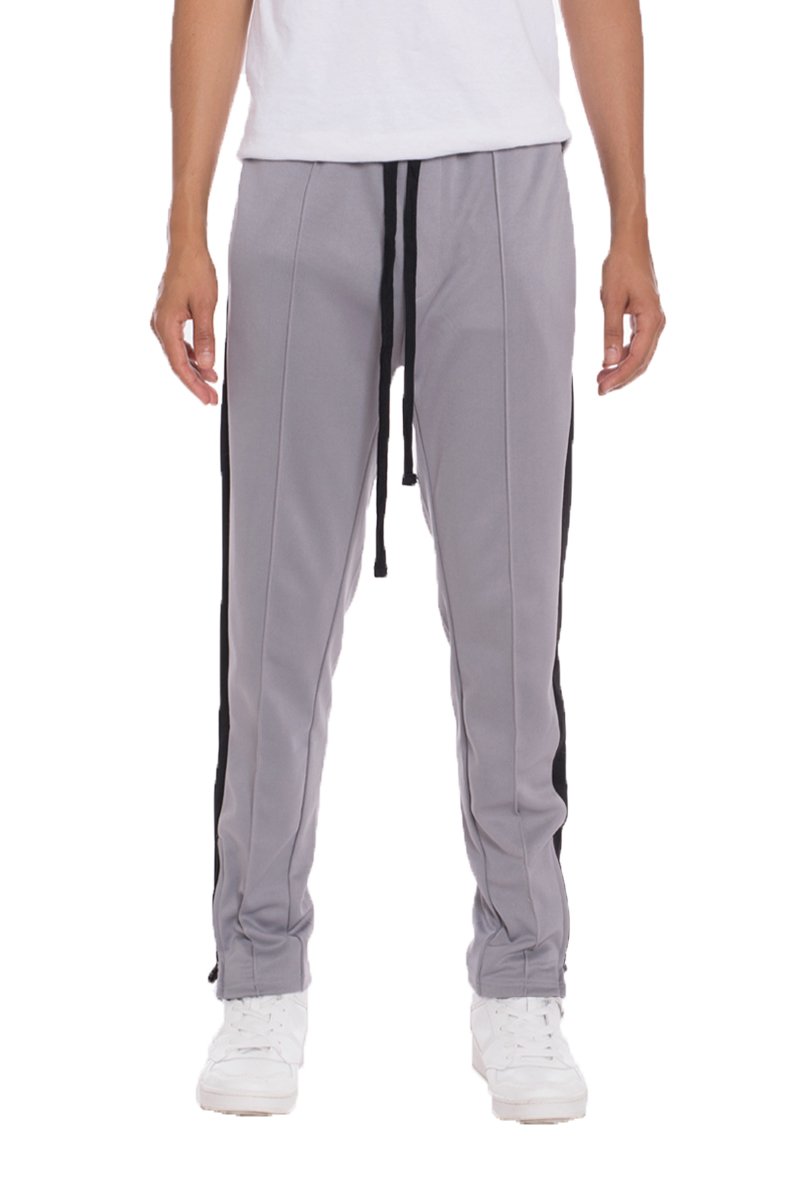 A pair of TRICOT Striped Track Pants featuring a stylish striped design, standard pockets, and a hidden ankle zipper, displayed on a model.