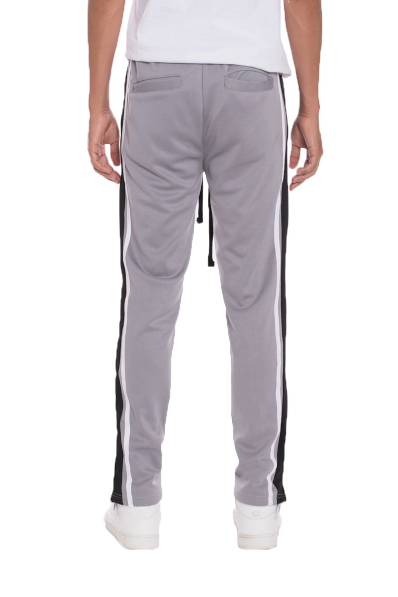 A pair of TRICOT Striped Track Pants featuring a stylish striped design, standard pockets, and a hidden ankle zipper, displayed on a model.