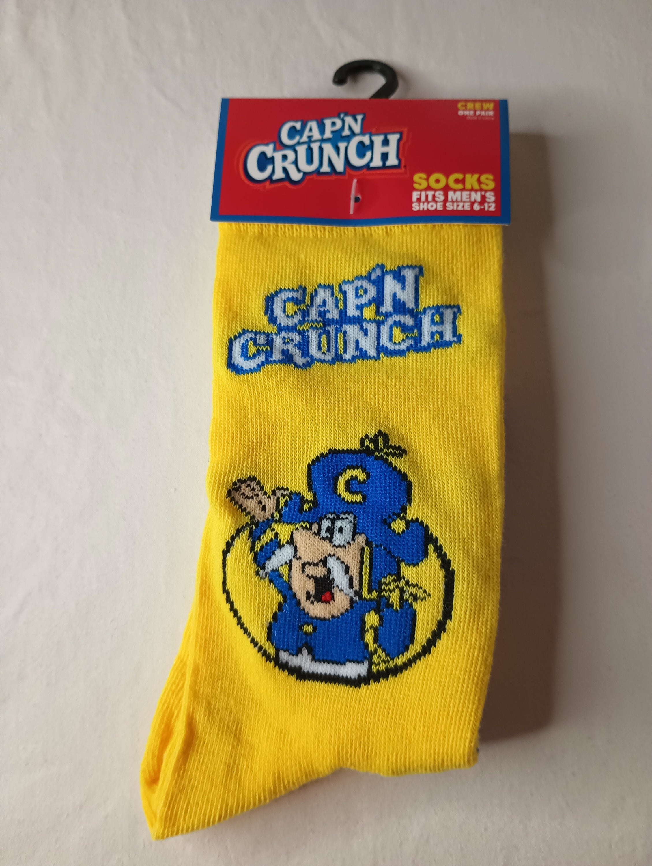 Cap'n Crunch Crew Socks in vibrant yellow and blue colors, designed for men's shoe sizes 6-12, made from polyester and spandex.