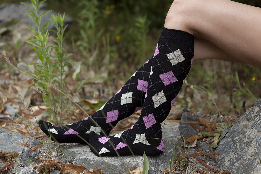 A pair of Women's Natural Black Argyle Knee High Socks featuring a trendy argyle pattern, perfect for stylish outfits.