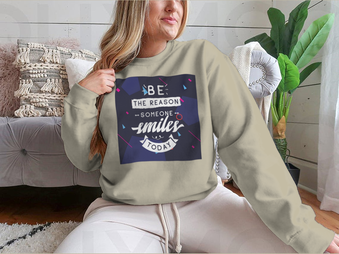 A cozy sweatshirt featuring the inspirational phrase 'Be The Reason Someone Smiles Today' in a stylish design, perfect for casual wear.