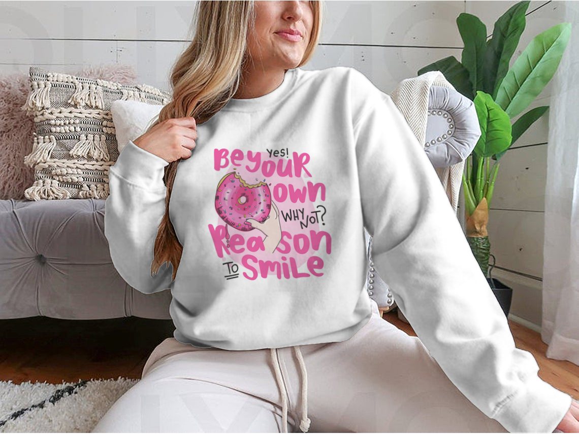 A cozy sweatshirt featuring the phrase 'Be Your Own Reason To Smile' in a stylish design, perfect for casual wear.