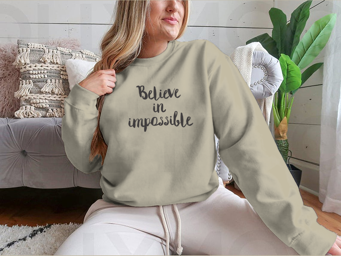 A stylish sweatshirt featuring the motivational phrase 'Believe In Impossible' designed for comfort and inspiration.