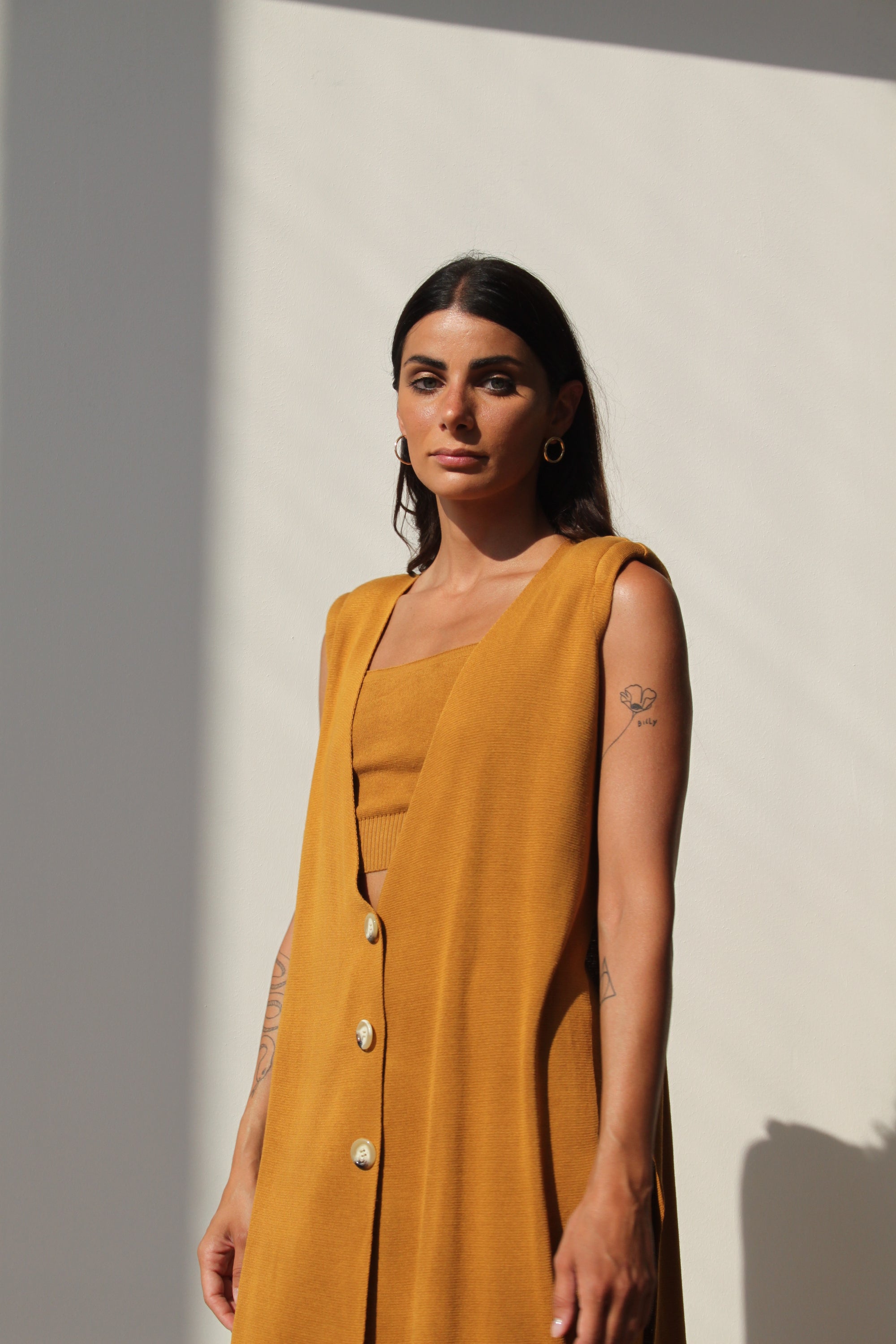 Elegant Camilla Gilet in gold color with structured shoulders and side slits, showcasing a stylish design.