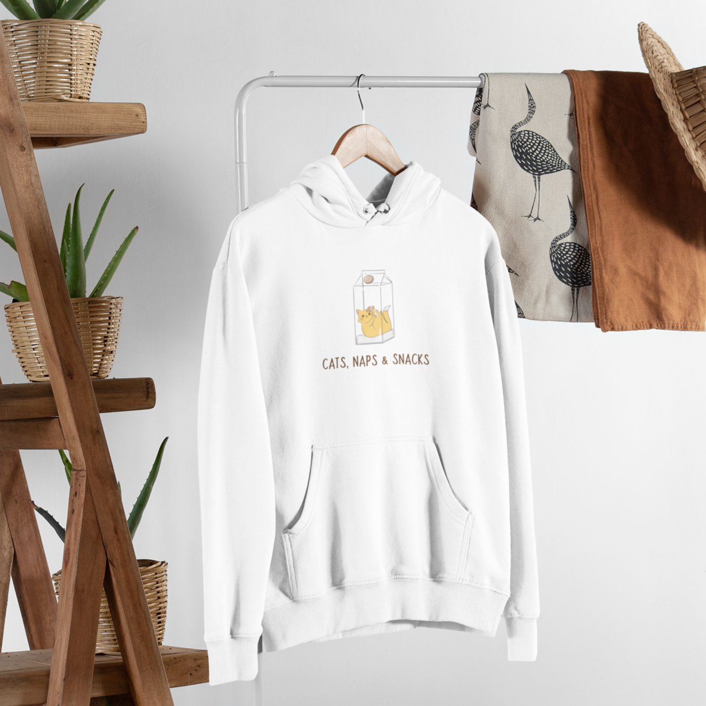 A cozy unisex hoodie made from organic cotton, featuring a playful design that celebrates cats, naps, and snacks, perfect for casual wear.