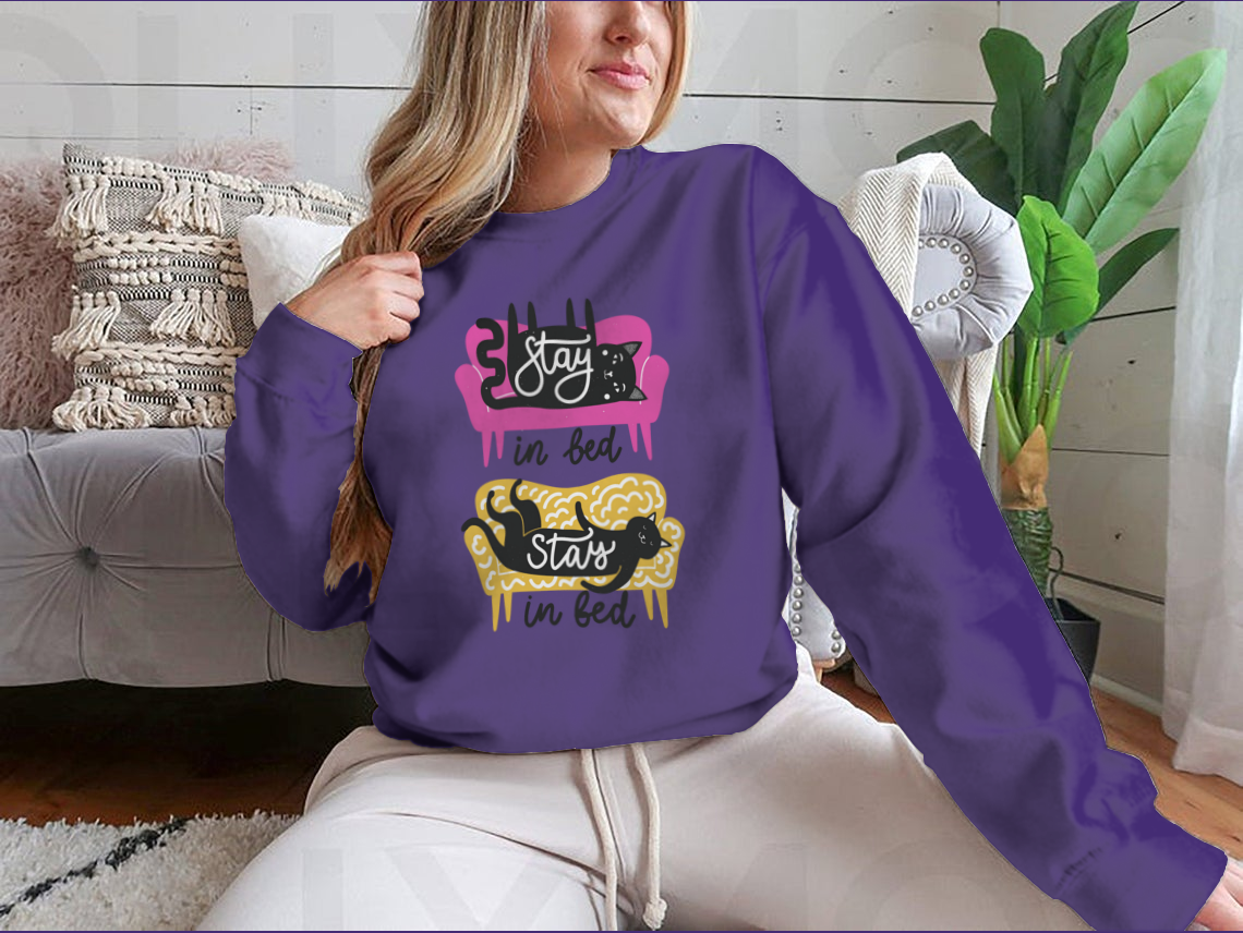 A cozy apparel featuring cats on a sofa with the text 'Stay In Bed', perfect for cat lovers.