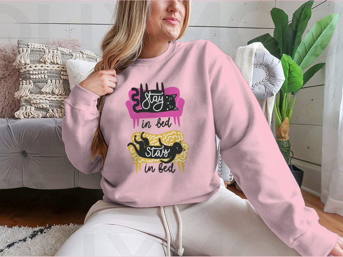A cozy apparel featuring cats on a sofa with the text 'Stay In Bed', perfect for cat lovers.