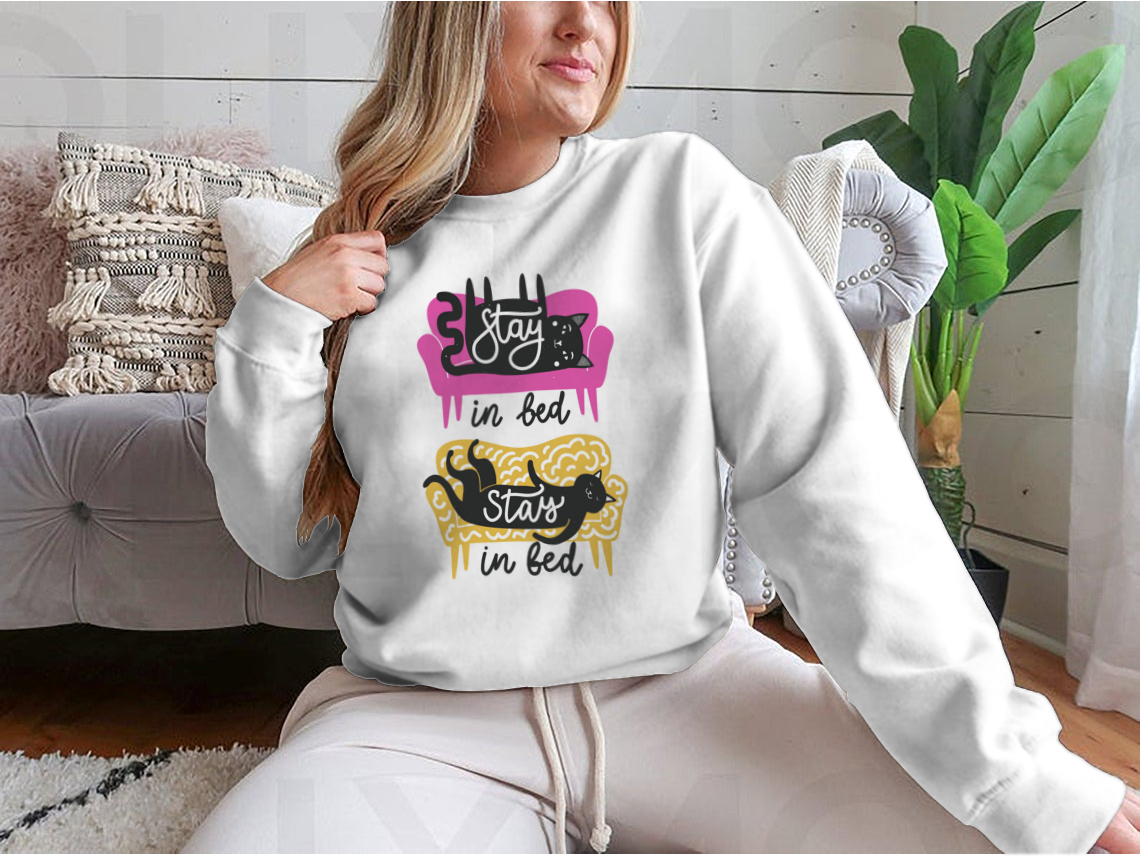A cozy apparel featuring cats on a sofa with the text 'Stay In Bed', perfect for cat lovers.