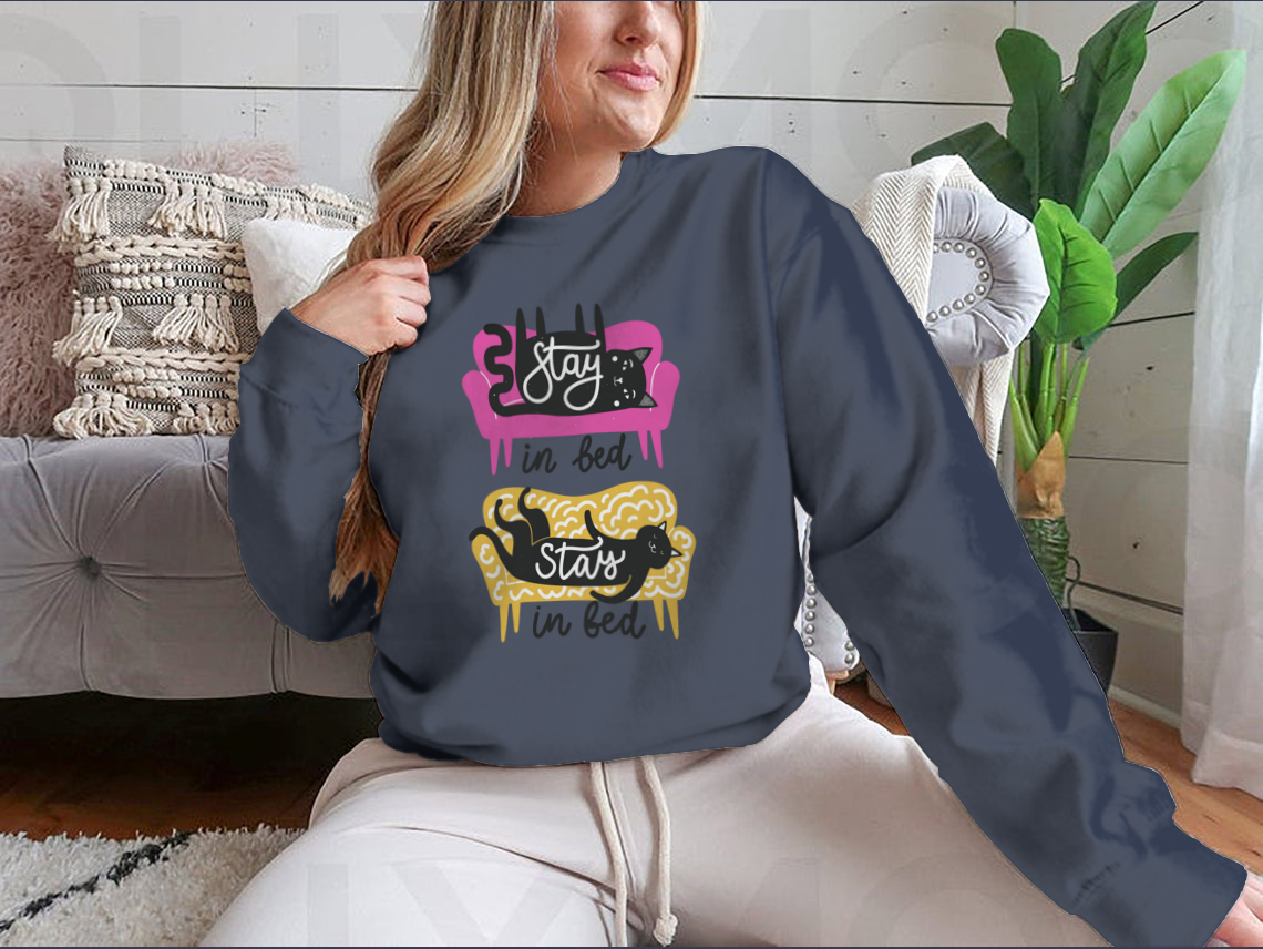 A cozy apparel featuring cats on a sofa with the text 'Stay In Bed', perfect for cat lovers.