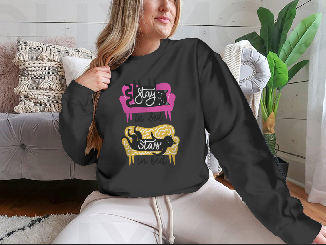 A cozy apparel featuring cats on a sofa with the text 'Stay In Bed', perfect for cat lovers.