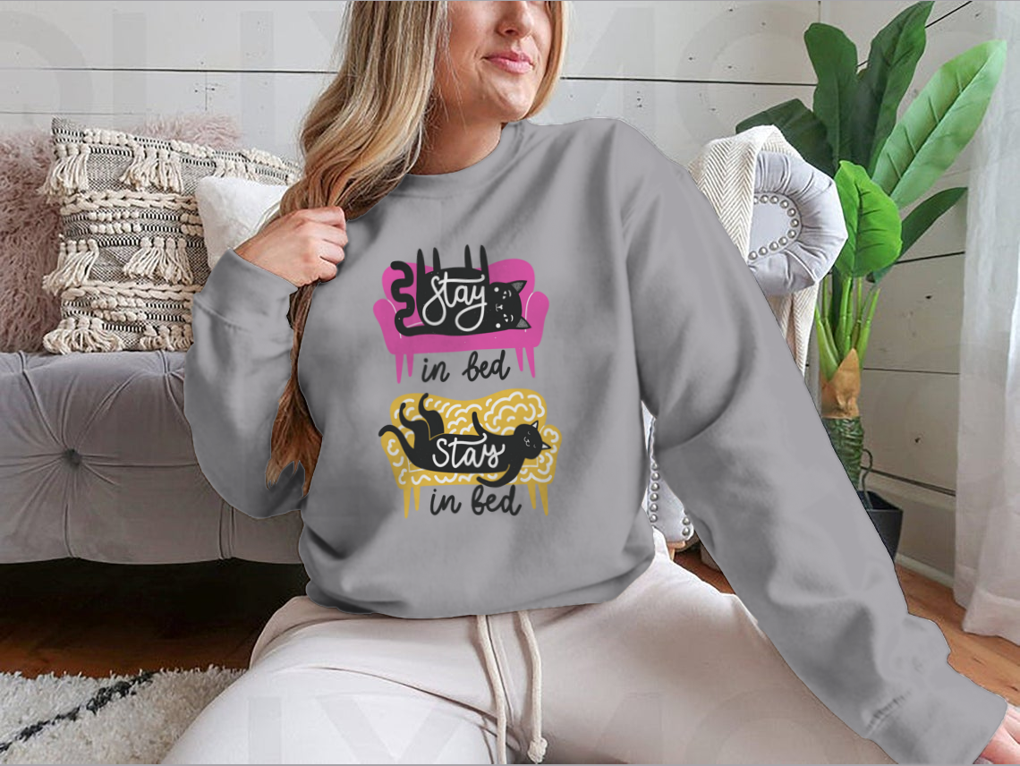 A cozy apparel featuring cats on a sofa with the text 'Stay In Bed', perfect for cat lovers.