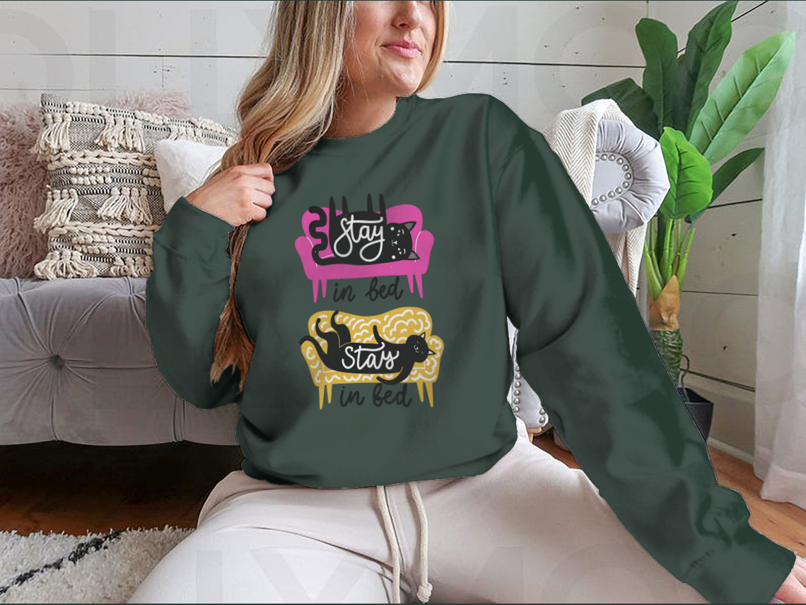 A cozy apparel featuring cats on a sofa with the text 'Stay In Bed', perfect for cat lovers.
