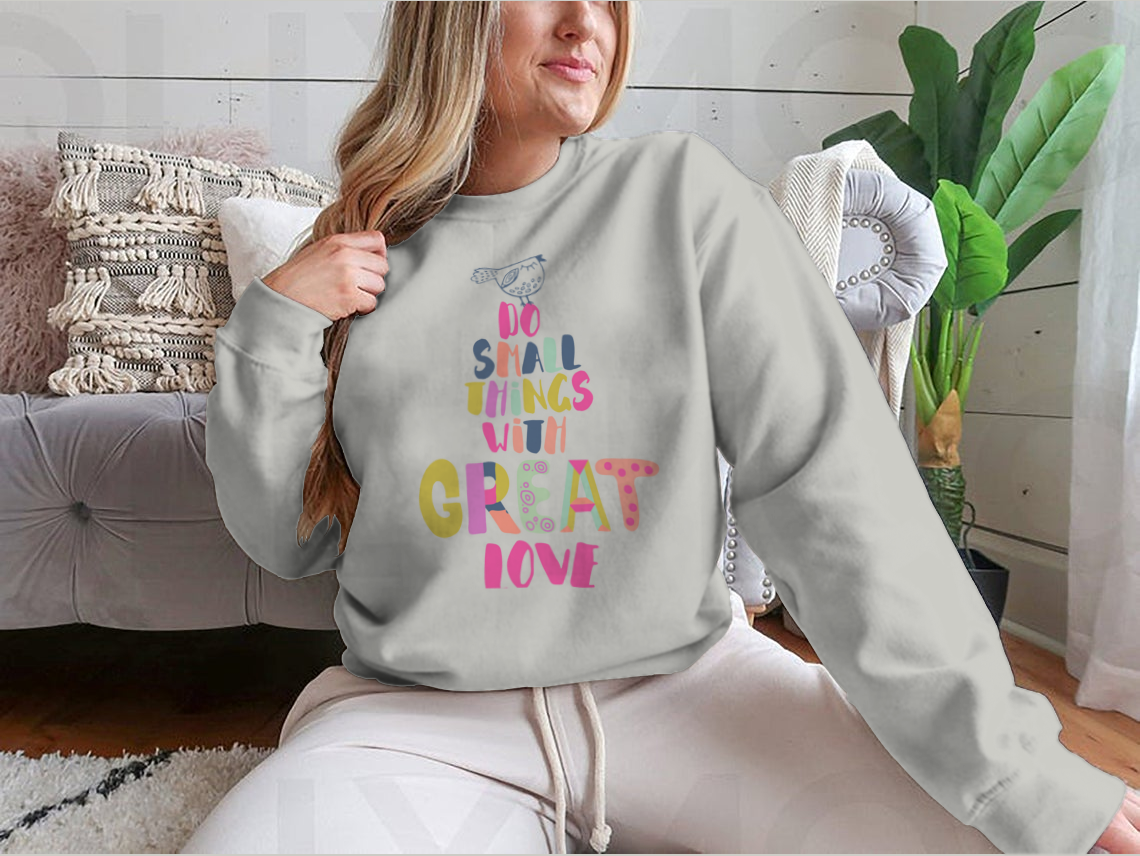 A cozy sweatshirt featuring the inspirational phrase 'Do Small Things With Great Love' in a stylish design, perfect for casual wear.