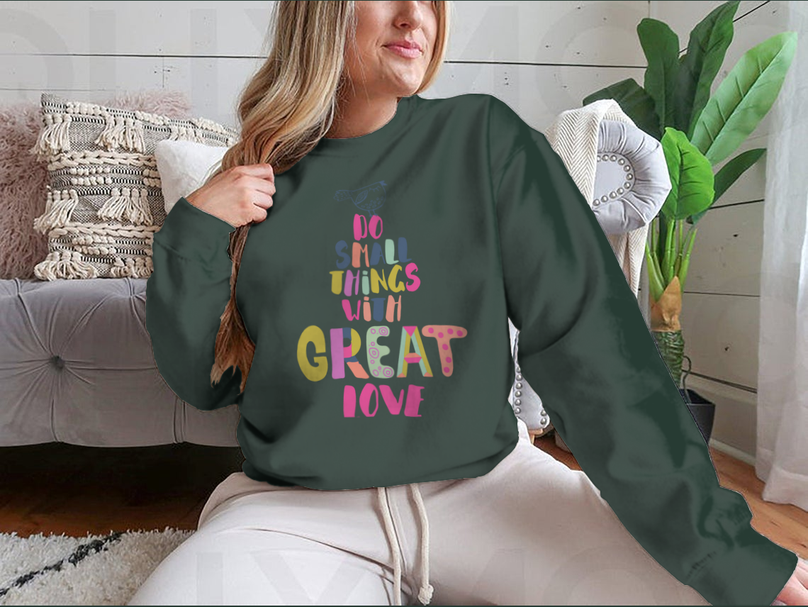 A cozy sweatshirt featuring the inspirational phrase 'Do Small Things With Great Love' in a stylish design, perfect for casual wear.