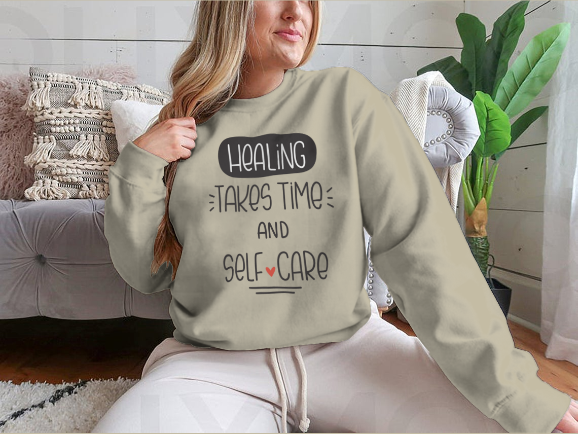 A cozy sweatshirt featuring the quote 'Healing Takes Time And Self-Care' in a stylish vector design, perfect for casual wear.